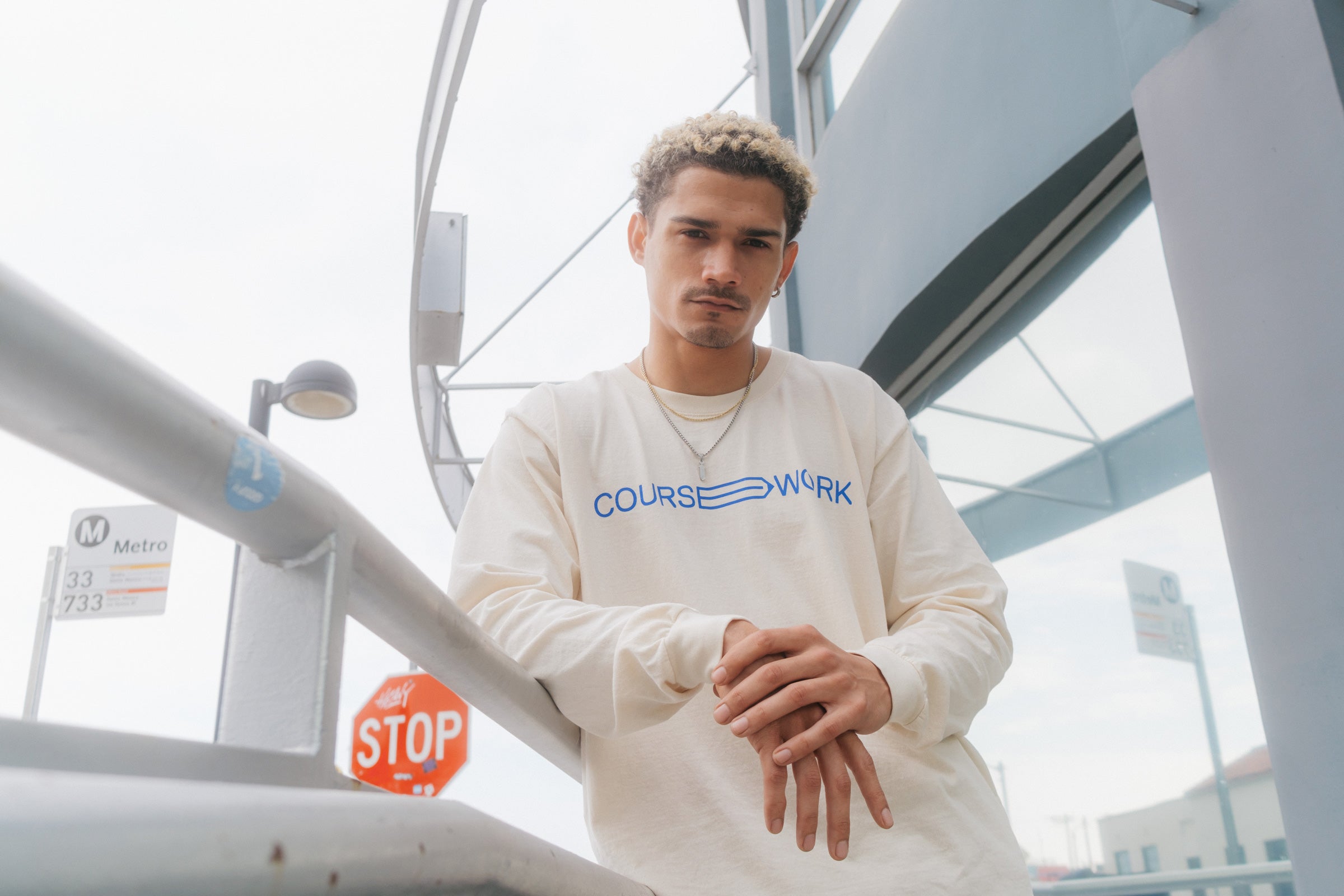 Model wearing the Full Width Text Long Sleeve Tee and leaning on a handrail.