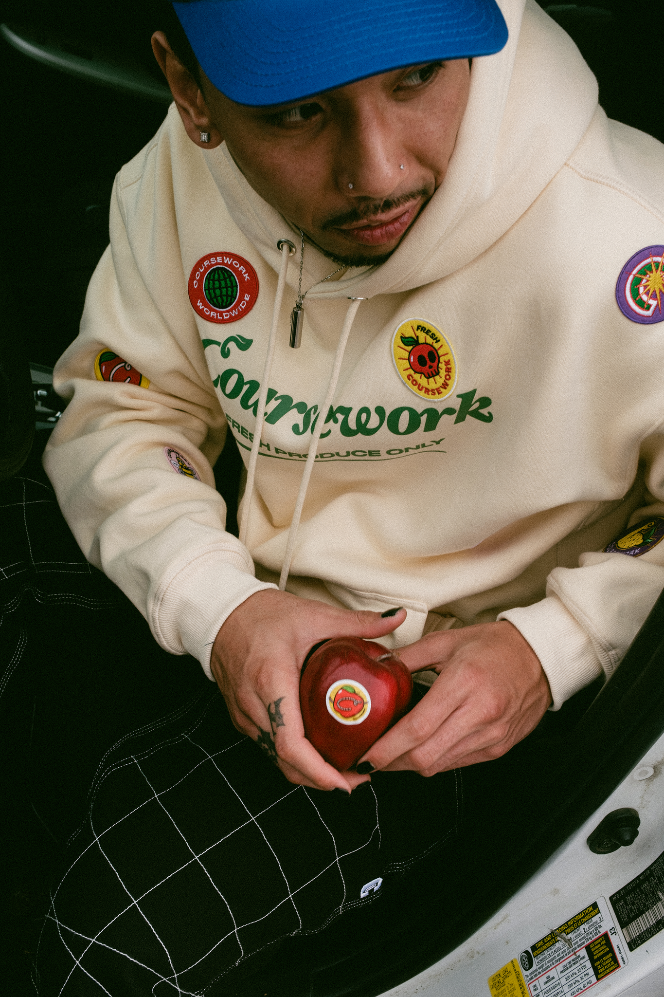 Model sits in car and holds an apple in his hands