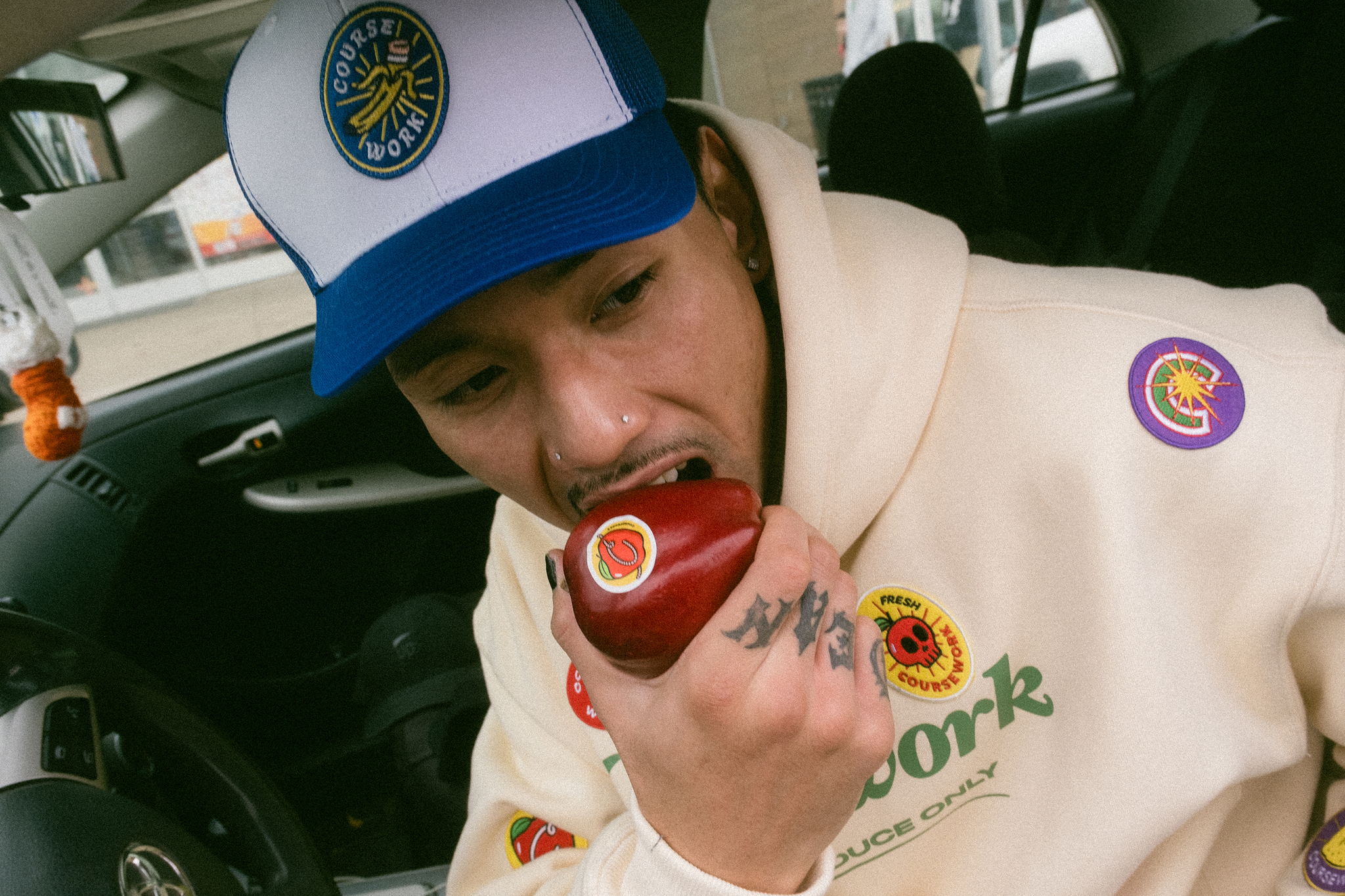 Model sits in car and takes a bite out of an apple