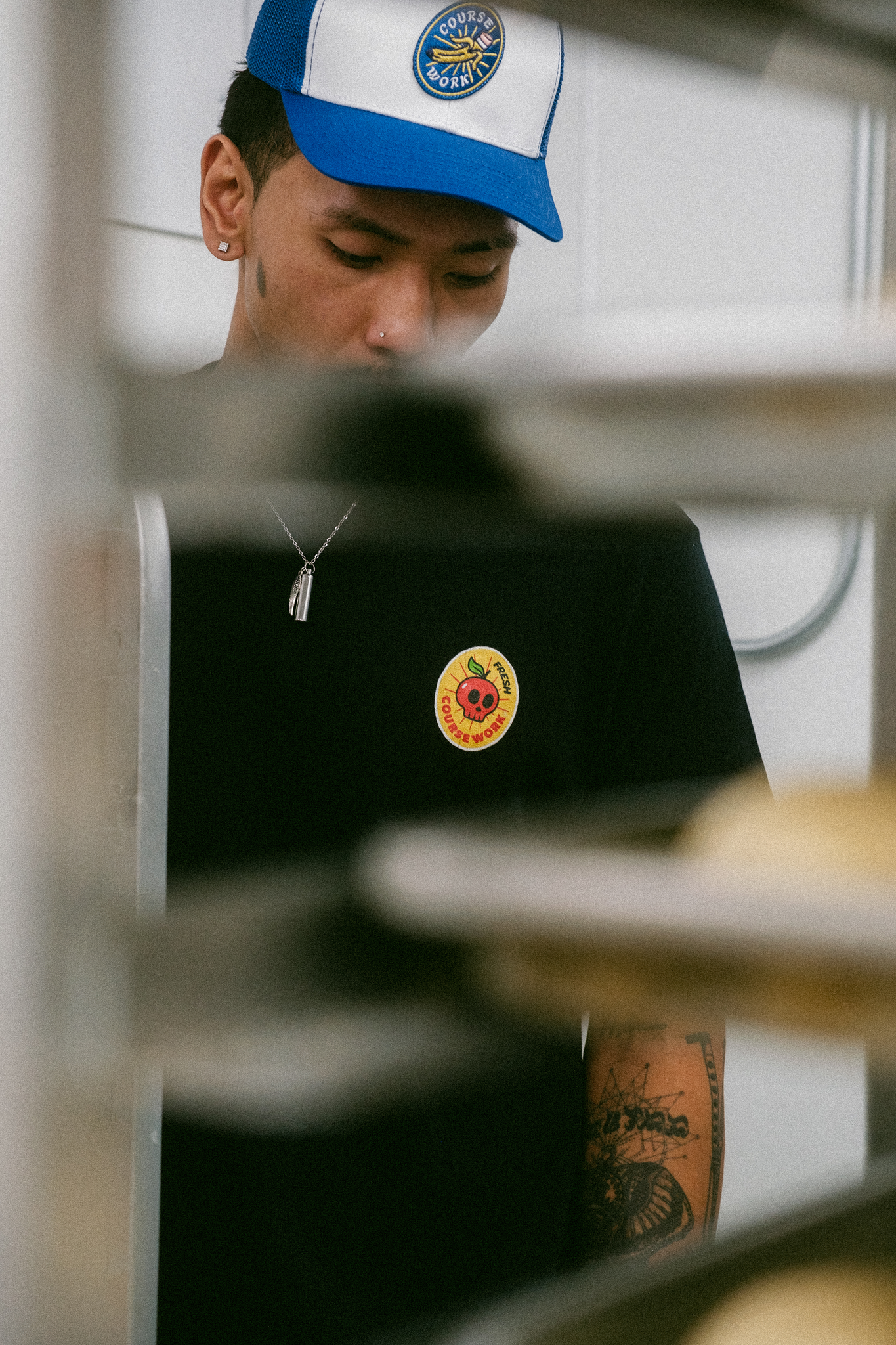 Model is looking down toward his t-shirt and a metal cart is placed in front of him in the foreground