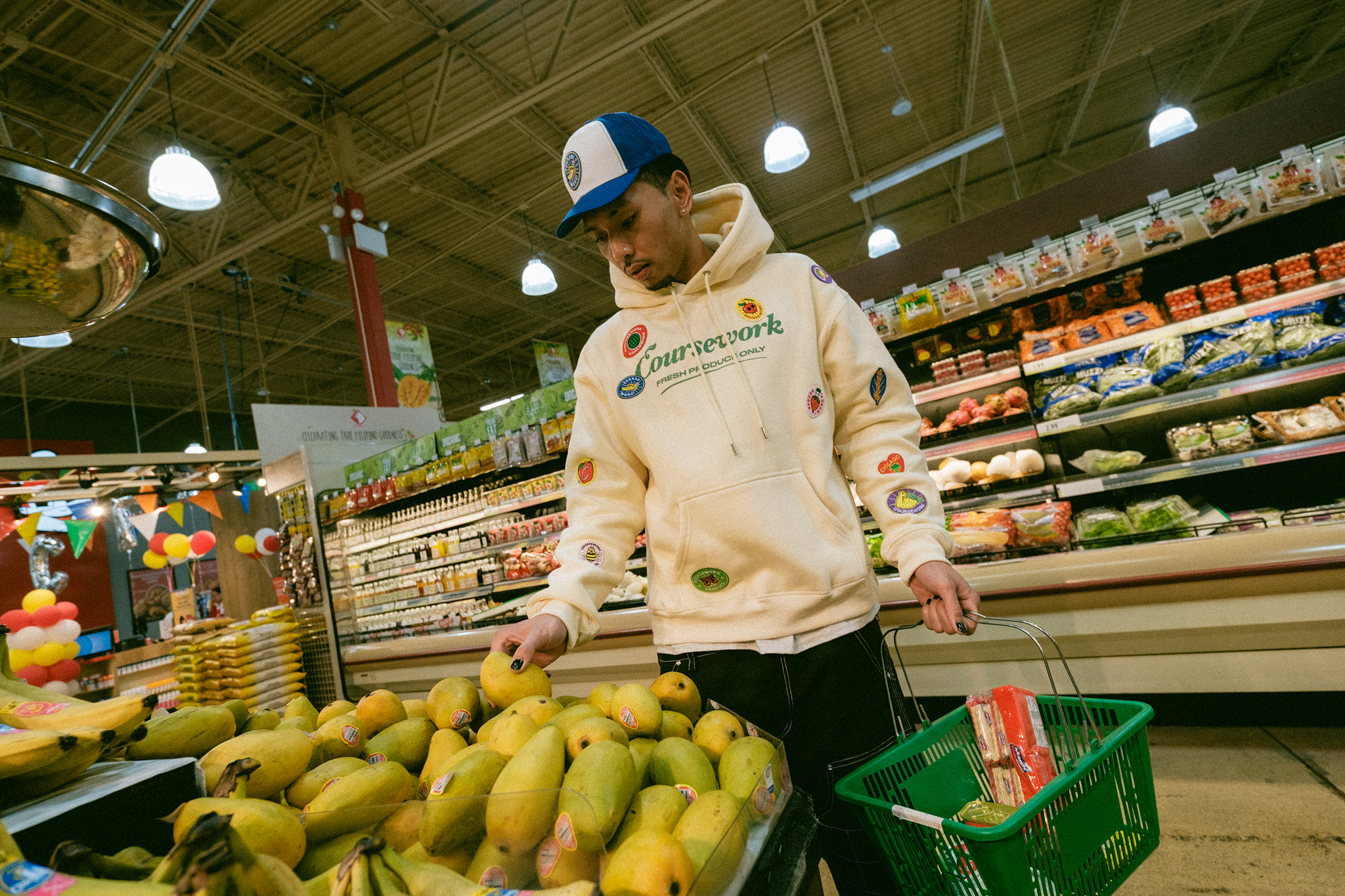 Model picking out mangos at the grocery store