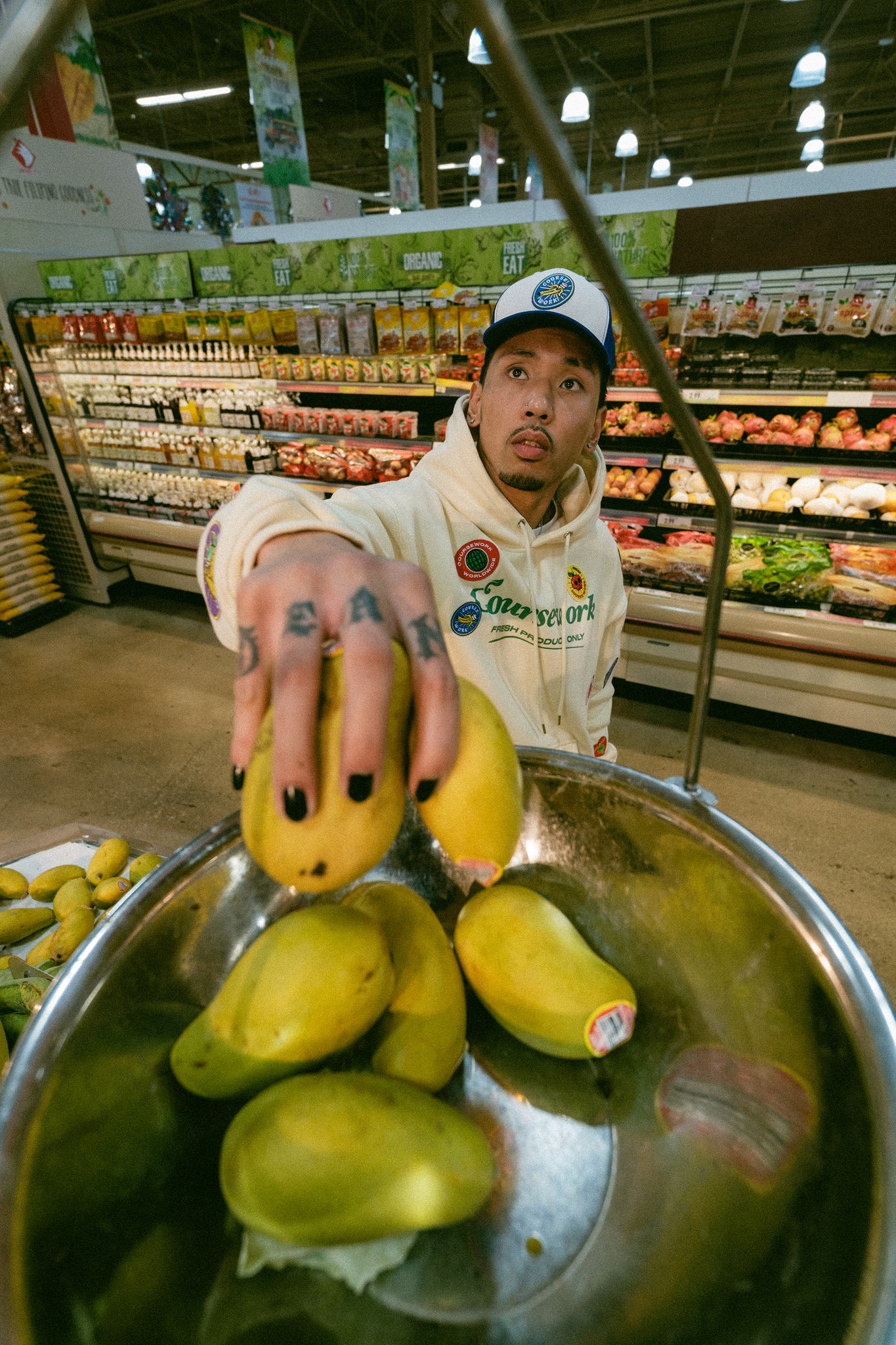 Model weighing mangos on a scale at the grocery store