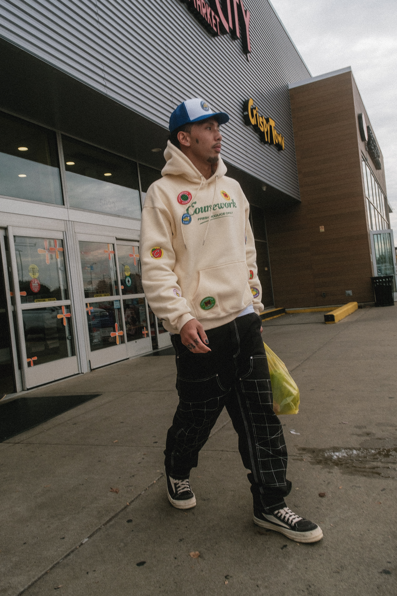 Model walks out of the grocery store with grocery bag in hand