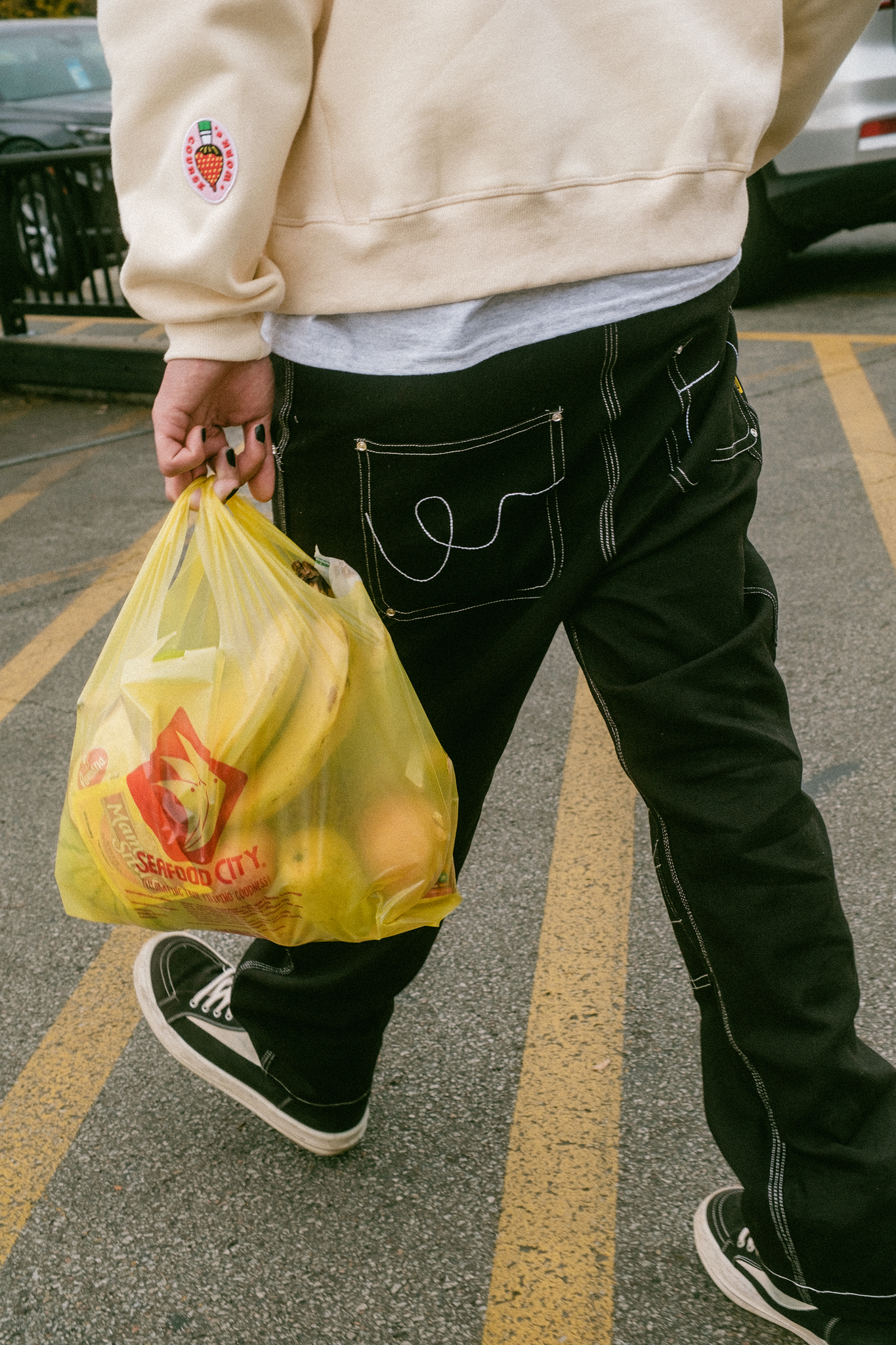 Pants shot of model walking back to car carrying grocery bag